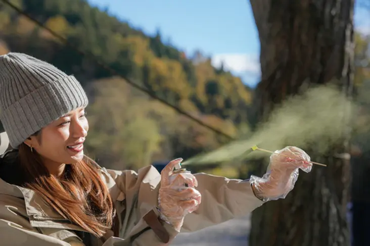 ルアーに塗装スプレーを吹き付けるする女性