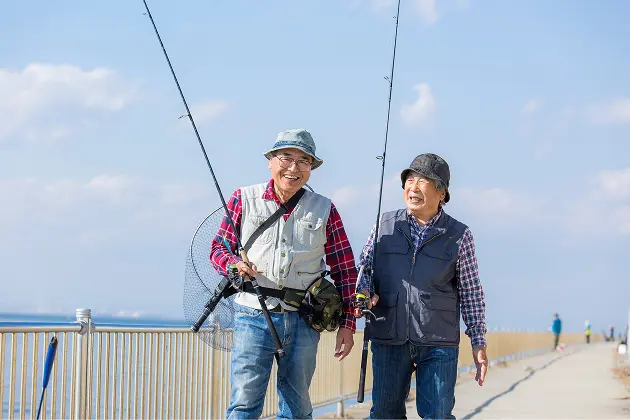 初老の男性二人が談笑しながら釣りに向かう様子